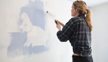 woman painting wall white using a paint roller