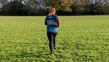 view of runner from behind wearing rspca sponsored t-shirt running in a field © RSPCA