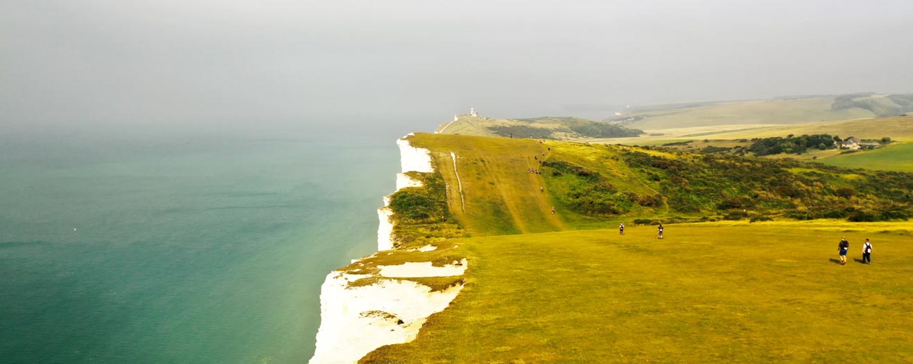 Scattered people walking the along the South Downs from Eastbourne towards Brighton.