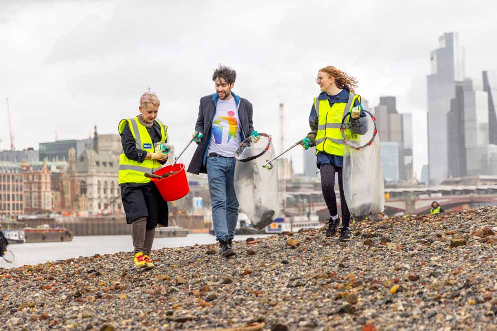 Three beach clean participants picking up litter from a shingle beach.