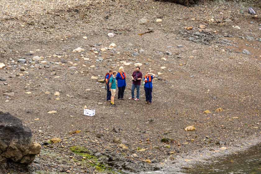 RSPCA team members standing on a rocky shoreline during a wildlife rescue visit.