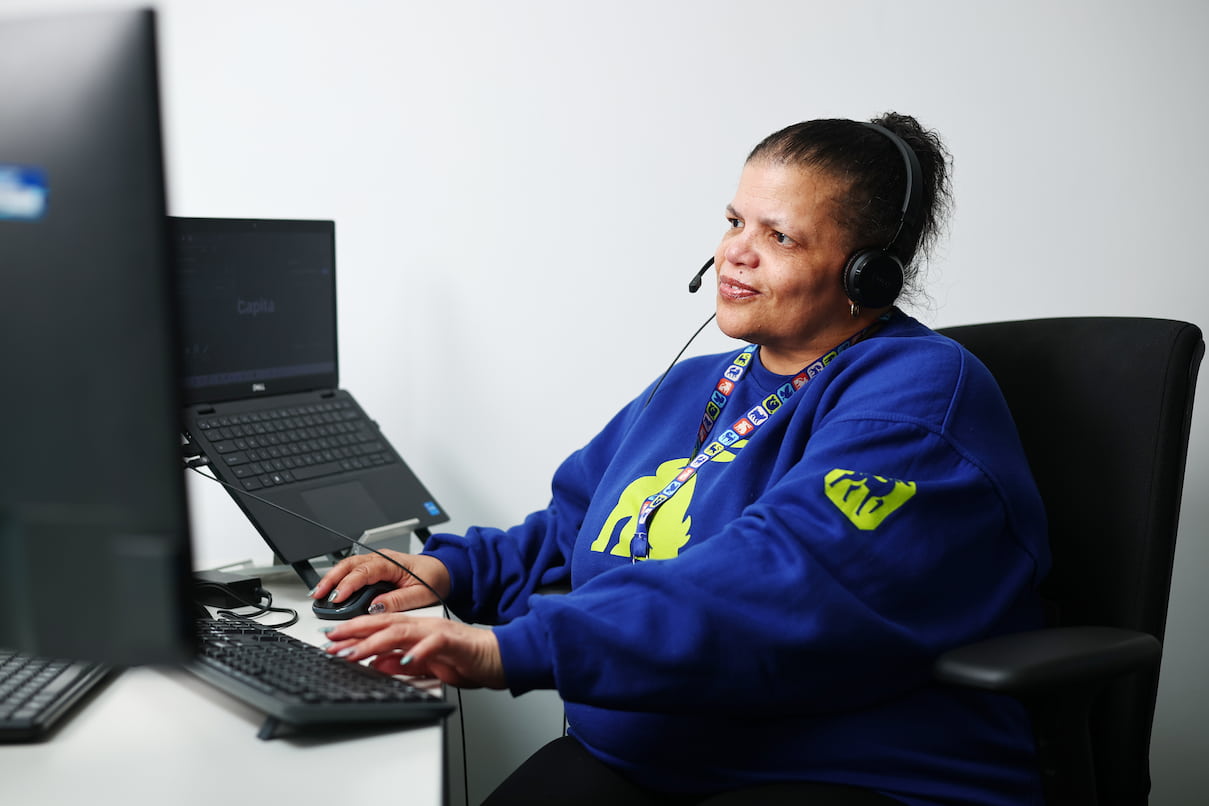 An RSPCA staff member wearing a headset working on a computer.