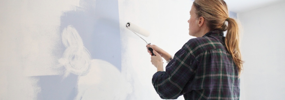 woman painting wall white using a paint roller © RSPCA