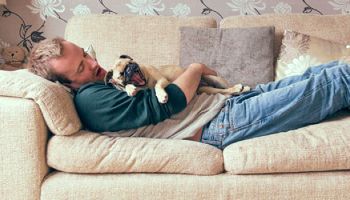 Man cuddled up with rehomed dog on the sofa