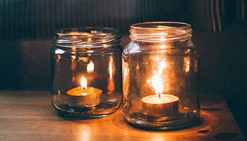Two lighted glass jar candles © AdriannaCalvo