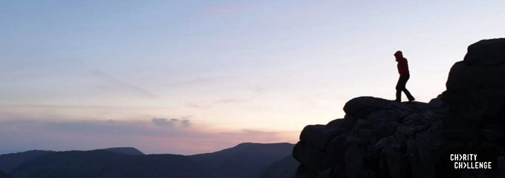 hiker on top of a mountain ledge at sunrise © RSPCA