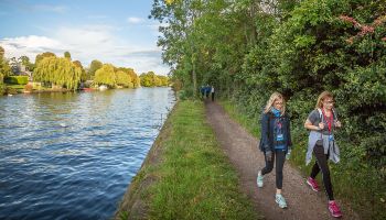 two women walking the thames path challenge with river thames by their side