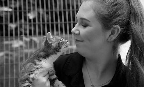 young woman holding a cat and smiling at it