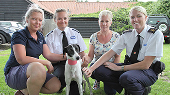 three rspca workers kneeling down with dog and owner outside