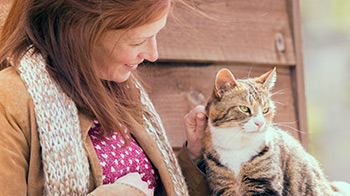 Woman stroking a cat outside © RSPCA