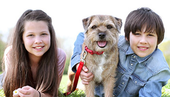 two children and dog lying on tummies outside © RSPCA