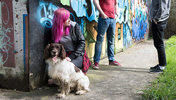 youths stood against a graffitied wall with a dog © RSPCA