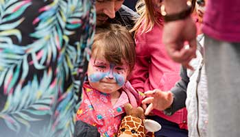 group of people with a little girl with a painted butterfly face in the middle