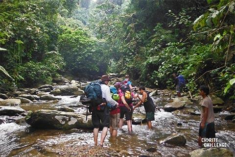 Trekkers on the Charity Challenge Sumatra Jungle Challenge trekking through a stream